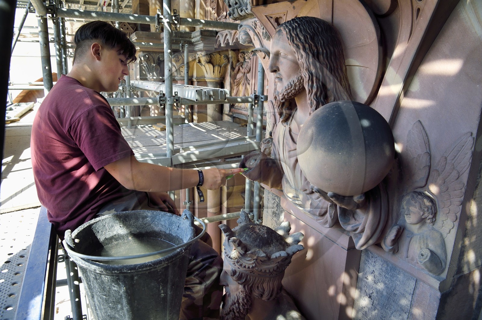 France, Bas Rhin, Strasbourg, old town listed as World Heritage by UNESCO, Notre Dame Cathedral, Judgment Day Portal Restoration Site, Christ Redeemer above King Solomon, cleaning the sculture with a toothbrush by a stonemason apprentice