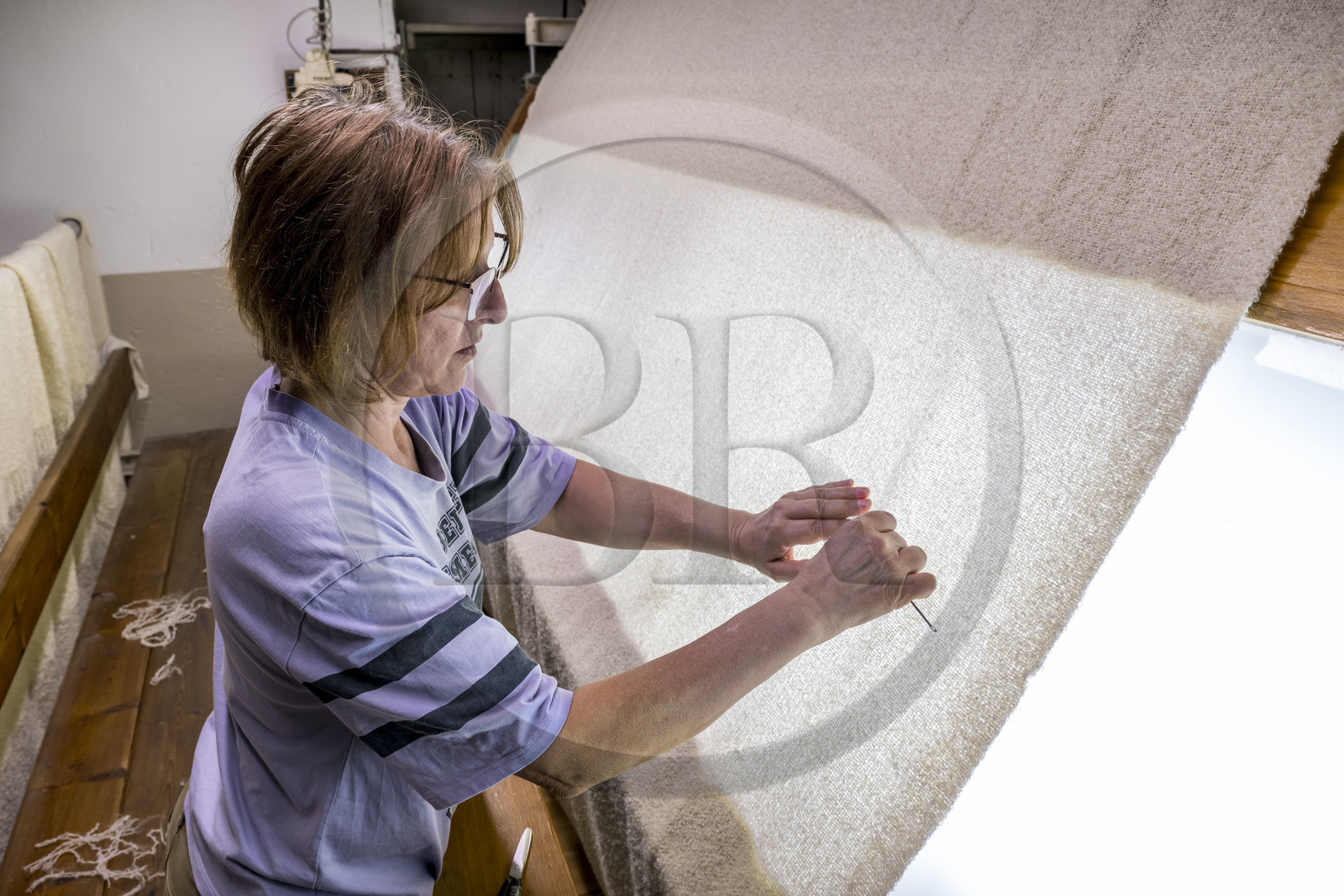 France, Vaucluse (84), L'Isle-sur-la-Sorgue, Manufacture Brun de Vian-Tiran, industrie textile lainière labellisée Entreprise du patrimoine vivant, atelier d'épincetage, ouvrière entrain d'enlever du tissus les défauts à la pince