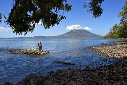Nicaragua, Ometepe Island in Lake Nicaragua, village of Merida, woman doing her laundry in the lake and the Conception volcano (1610 m) in the background