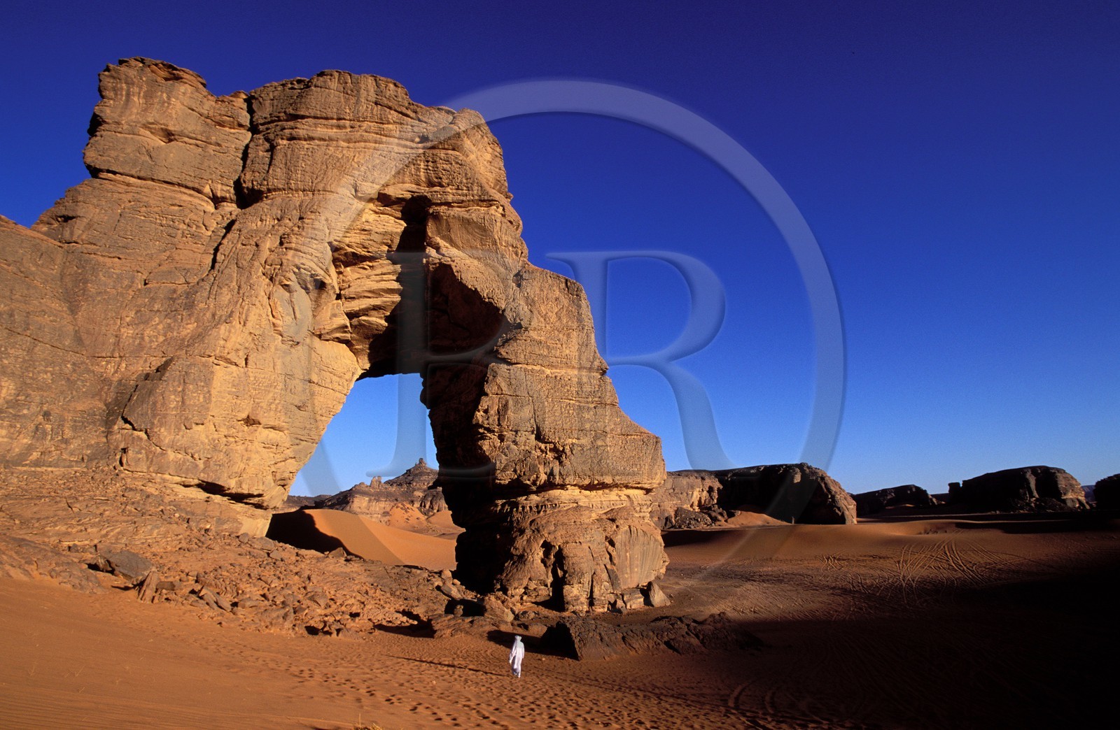 Libye, région du désert, Le Fezzan (Sahara), Touareg sous l'arche (en grès) de Afazedjar dans la Tadrart-Akakus