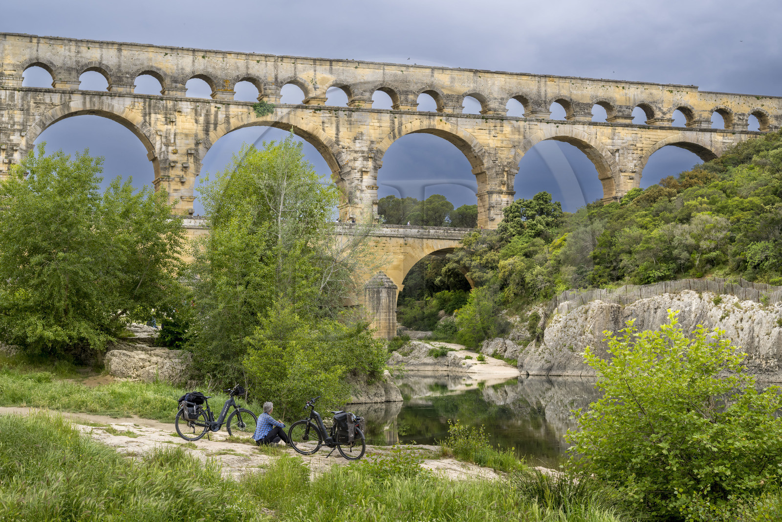 France, Gard, the Pont du Gard listed as World Heritage by UNESCO, Grand Site de France, cyclist taking a break in front of the Roman aqueduct bridge spanning the Gardon river