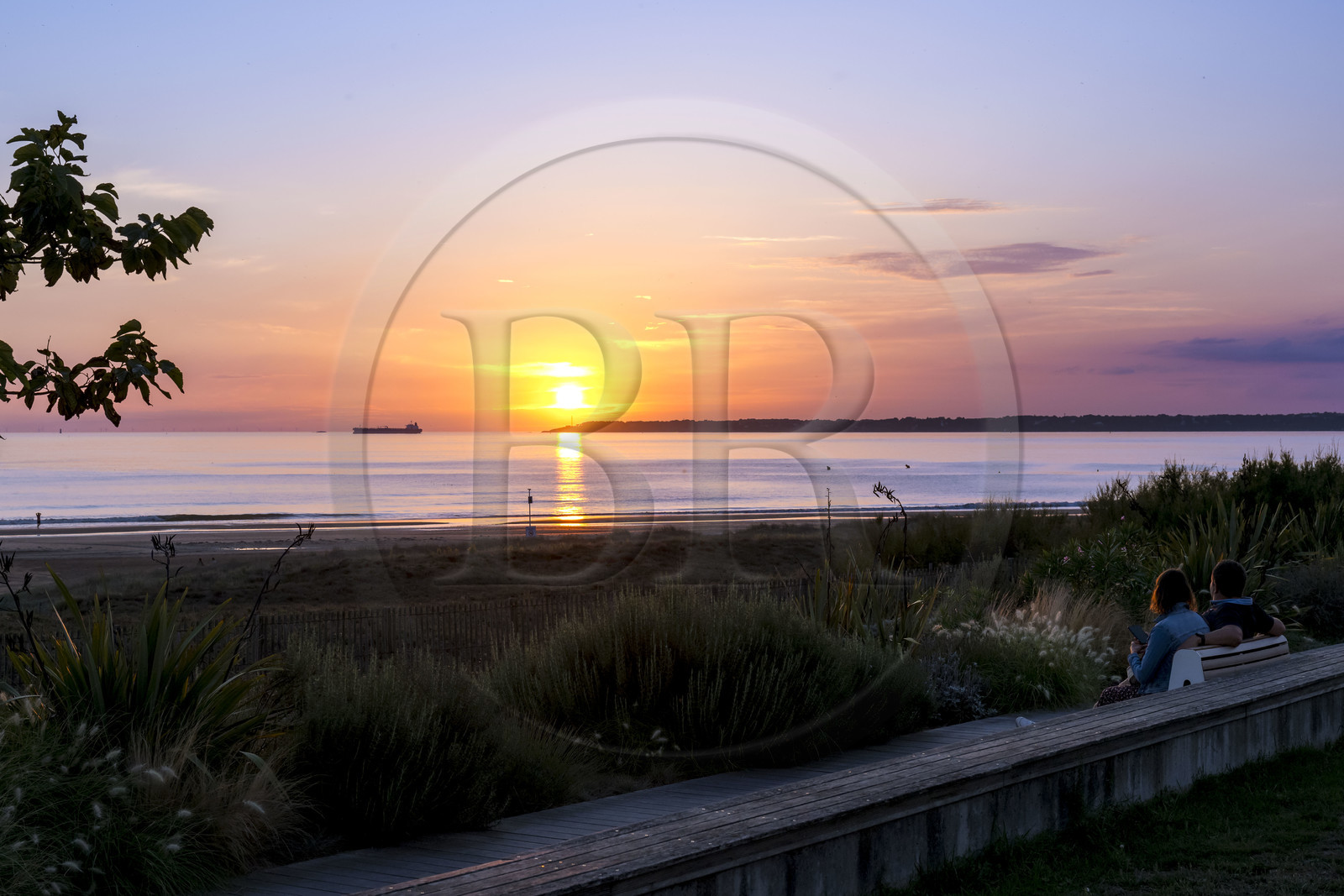 France, Loire-Atlantique (44), Saint-Brévin-Les-Pins, couple sur un banc de la promenade de bord de mer, navire quittant l'estuaire de la Loire pour l'océan en arrière plan