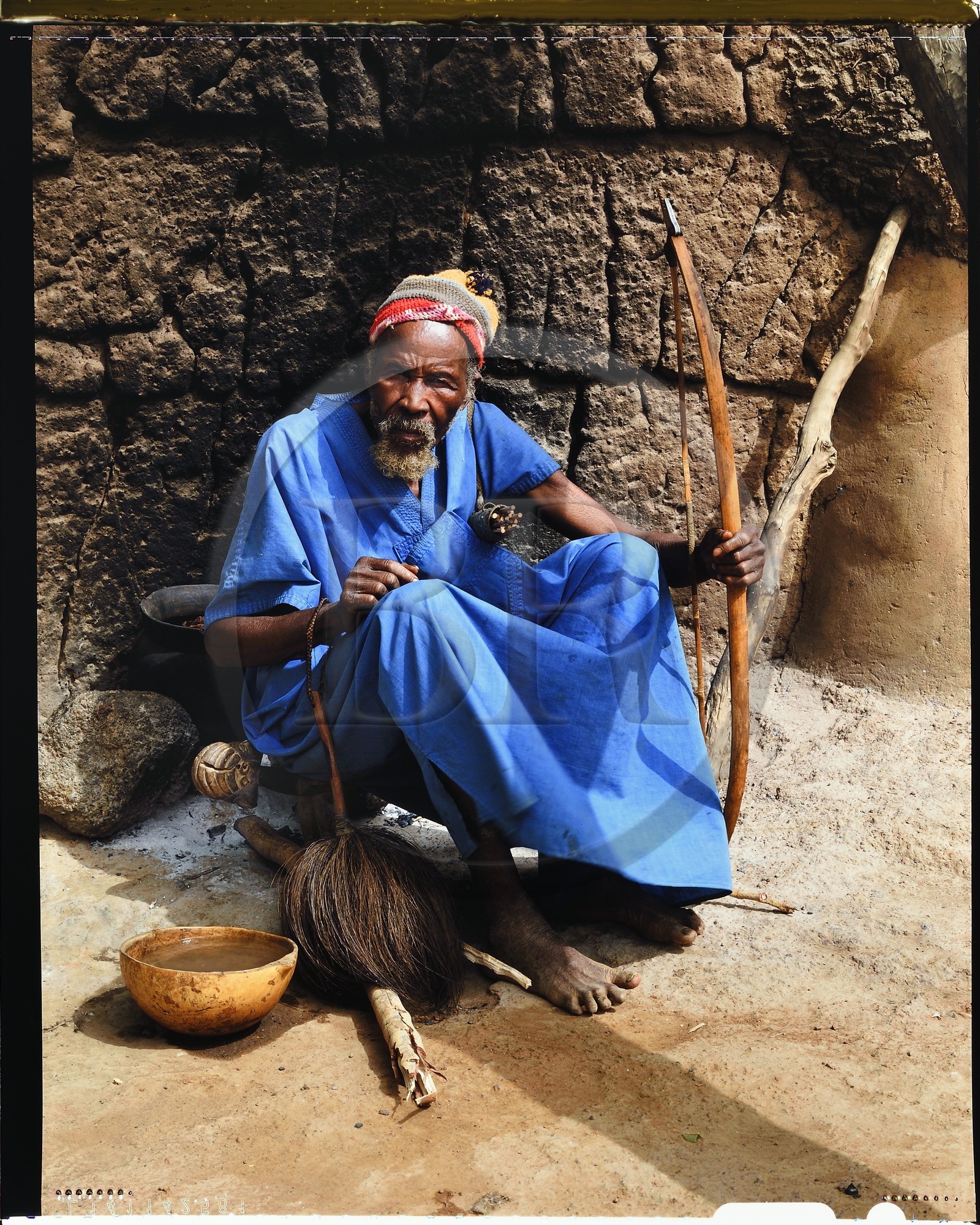 Burkina Faso, Poni province, Lobi land, Loropéni region, head of the village of Ouadara posing with its attributes (bow and arrows, fly swatter) and a calabash of millet (cereal) beer
