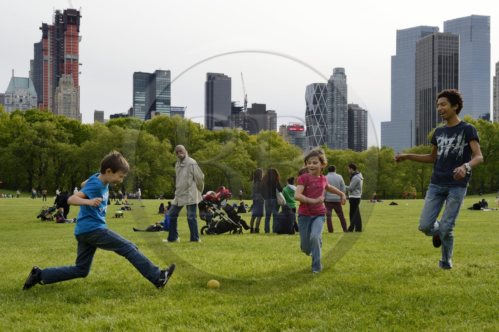 Etats-Unis, New York, Manhattan, Central Park, enfants jouant au football sur le Sheep Meadow, immeubles de Central Park Sud en arrière plan
