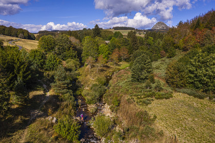 France, Ardèche (07), parc naturel régional des Monts d'Ardèche, Massif du Mézenc, randonneuse sur le sentier du GR 7 à la jonction de la Loire à droite et du Riu l'Aigue Negre à gauche, le Mont Gerbier-de-Jonc (1551 m) où la Loire trouve sa source en arrière plan (vue aérienne)