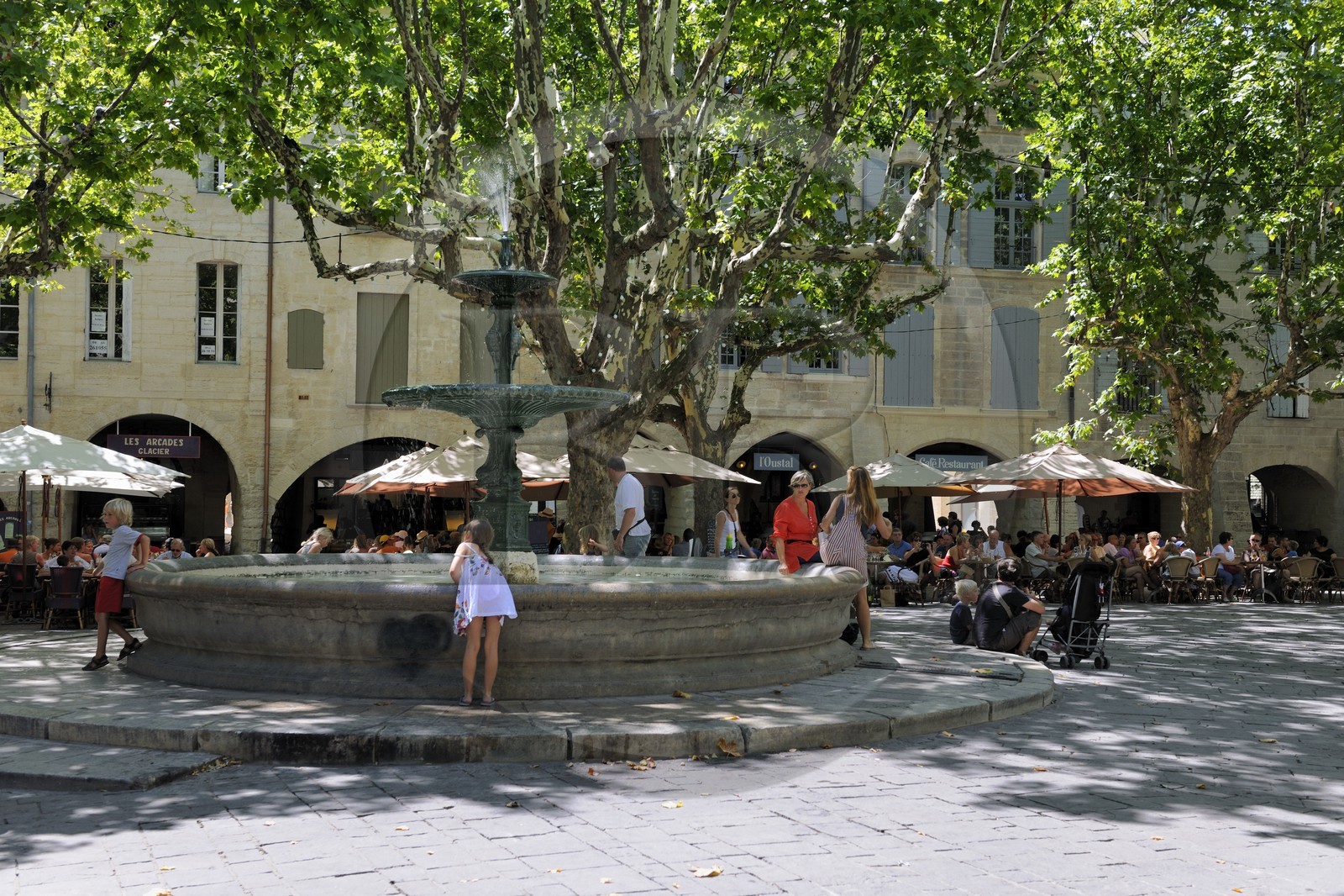 France, Gard (30), Uzès, classée ville d'art et d'histoire, fontaine de la Place aux Herbes entourée de maisons à arcades et ses terrasses de café