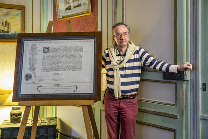 France, Ille-et-Vilaine (35), Côte d'Emeraude, Saint-Malo, l'Hotel Magon, authentique demeure de corsaire, hotel particulier construit pour François Auguste Magon de la Lande en 1725, armateur malouin, corsaire de Louix XV, négrier et directeur de la compagnie des Indes, son propriétaire actuel l'historien malouin Olivier Chereil de la Rivière à côté de la reproduction de la lettre de marque du corsaire L'Apollon de Rochefort