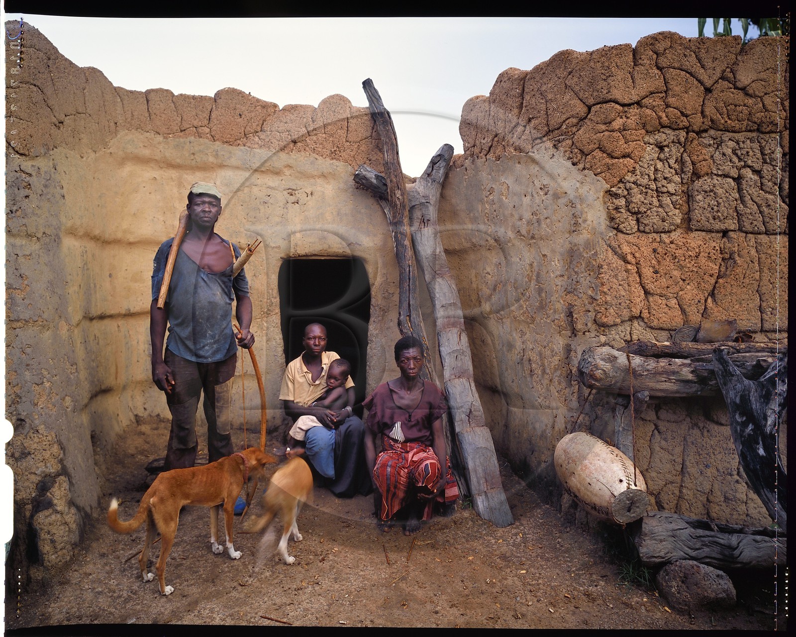 Burkina Faso, Poni province, Lobi land, Loropéni, peasant posing with bow and arrows with his two wives and his son in front of their house
