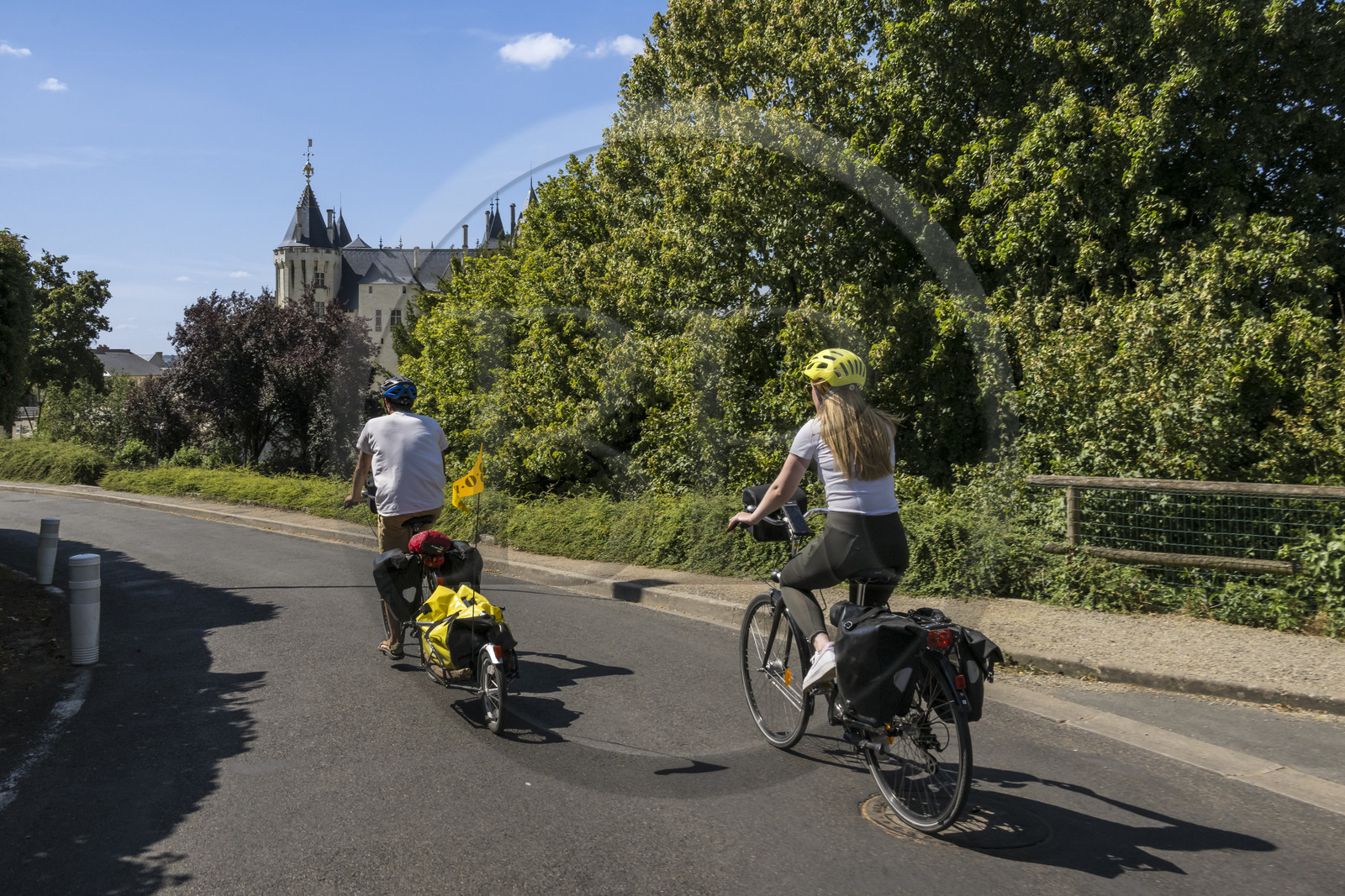 France, Maine-et-Loire, Loire valley listed as World Heritage by UNESCO, Saumur, cycling on the banks of the Loire, bike with a trailer carrying camping equipment, the castle in the background