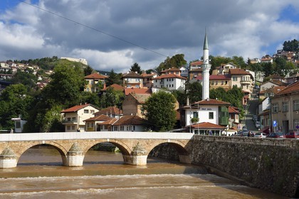 Bosnie-Herzégovine, Sarajevo, le pont Seher Cehaja sur la rivière Miljacka et la Maison du Défi à droite devant le minaret
