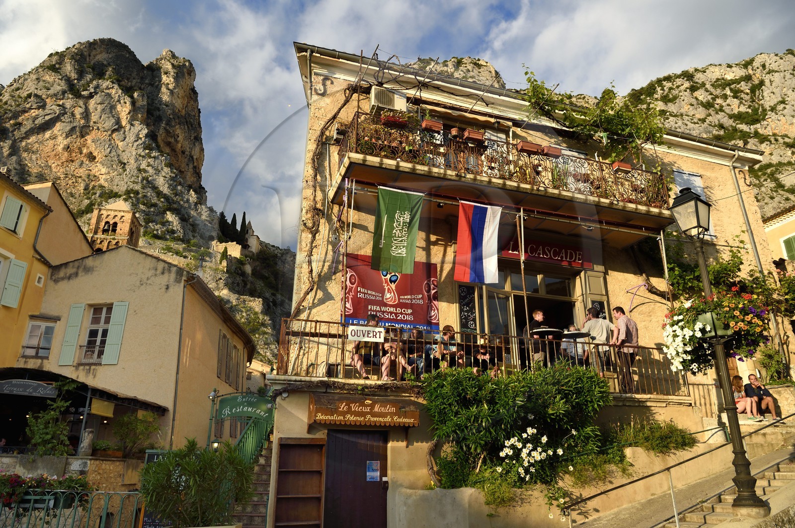 France, Alpes de Haute Provence, Parc Naturel Régional du Verdon, village of Moustiers Sainte Marie, labelled Les Plus Beaux Villages de France (The Most Beautiful Villages of France), café - restaurant in the village in the evening and the Star of Moustier hanging on a chain several tens of meters above the ground