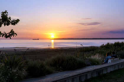 France, Loire Atlantique, Saint-Brévin-Les-Pins, couple on a bench on the seaside promenade, ship leaving the Loire estuary for the ocean in the background