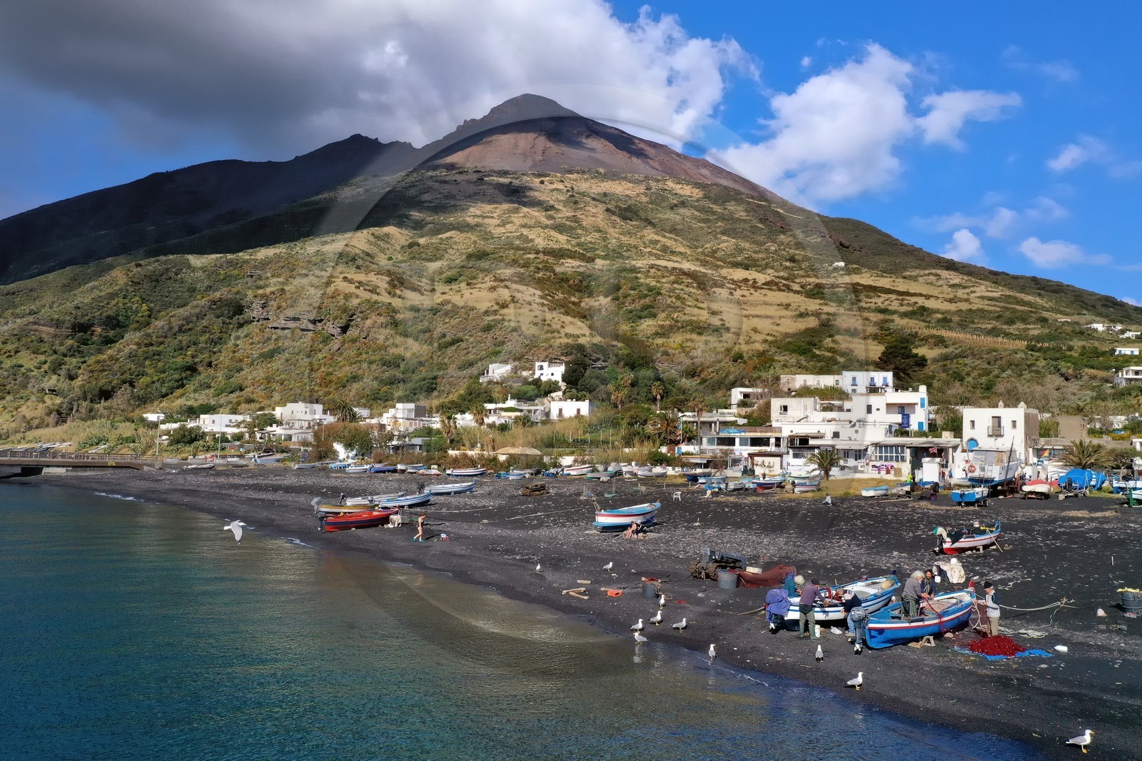 Italie, Sicile, iles Eoliennes, classées Patrimoine Mondial de l'UNESCO, ile de Stromboli, pecheurs sur la plage de Scari et le volcan actif du Stromboli en arrière plan (vue aérienne)