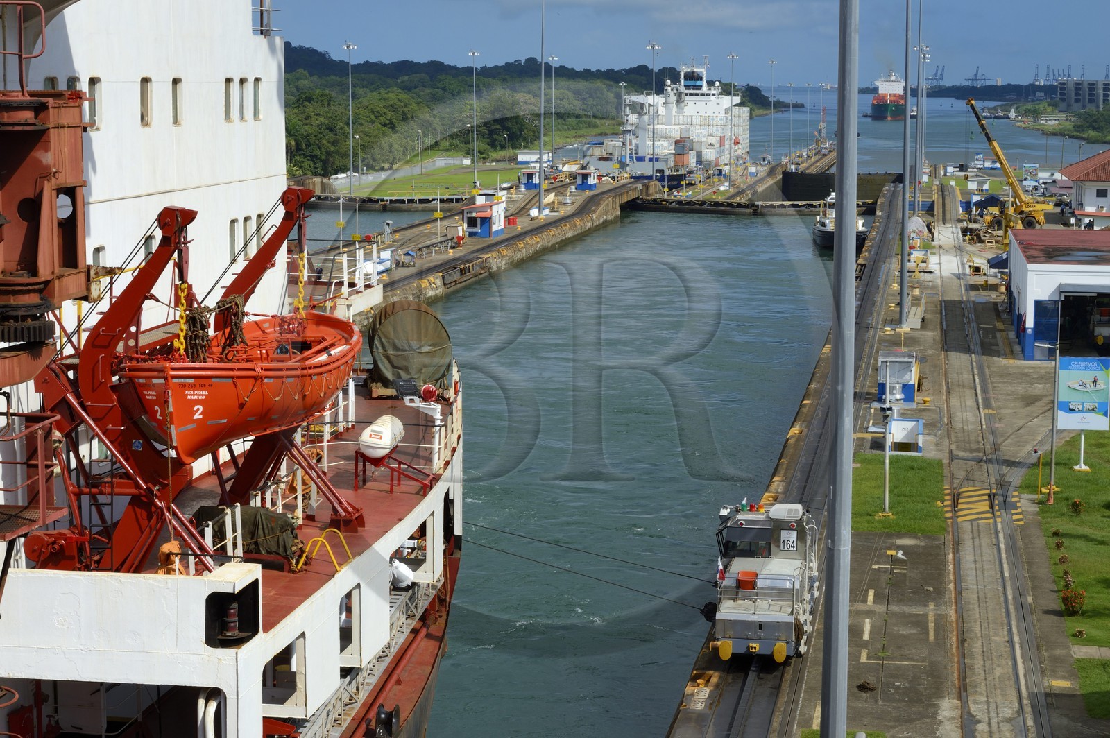 Panama, province de Colon, Canal de Panama, écluses de Gatun, mules mécaniques ou locomotives électriques guidant un cargo porte-conteneurs Panamax entre les murs de l'écluse