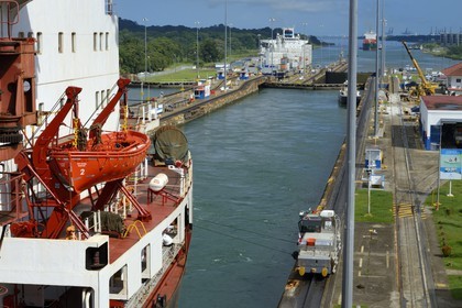 Panama, province de Colon, Canal de Panama, écluses de Gatun, mules mécaniques ou locomotives électriques guidant un cargo porte-conteneurs Panamax entre les murs de l'écluse