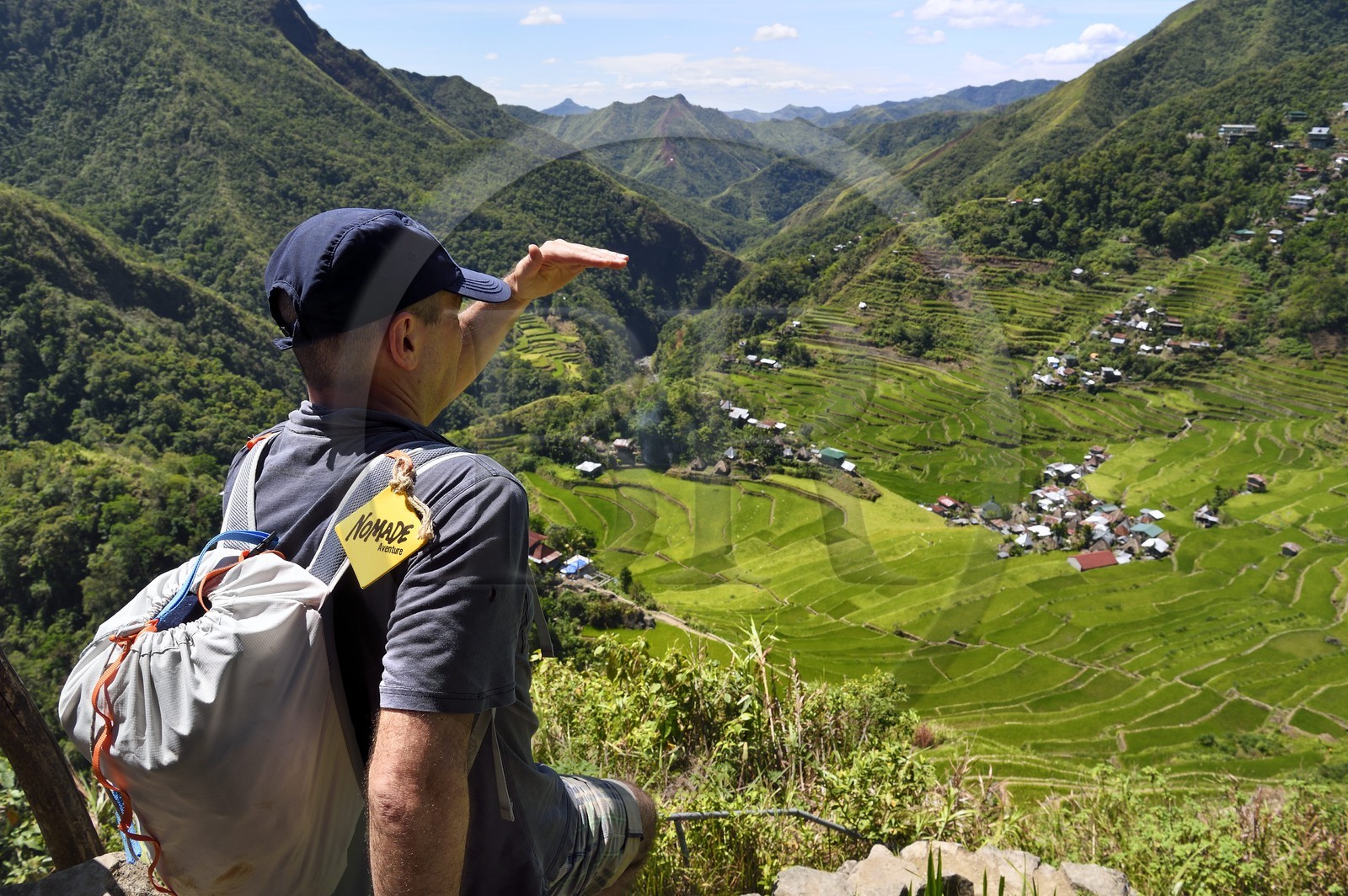 Philippines, province d'Ifugao, randonneur surplombant les rizières en terrasses de Banaue autour du village de Batad, classées Patrimoine Mondial de l'UNESCO, logo Nomade Aventures