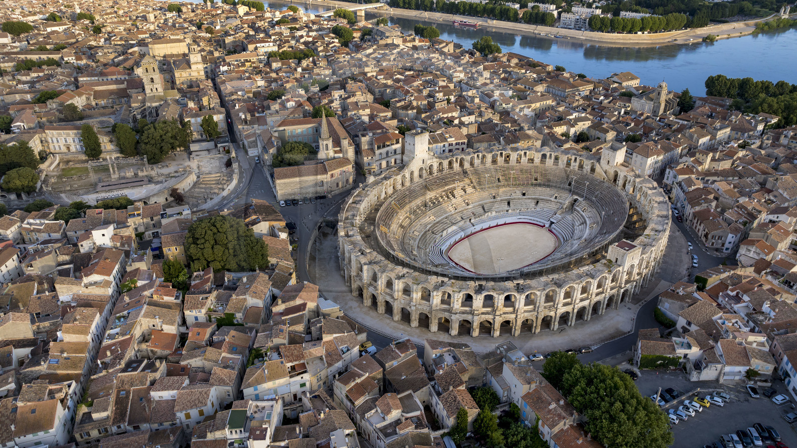 France, Bouches du Rhone, Arles, the Arena, a Roman amphitheater built around 80-90 AD, and the ancient theatre from the 1st century BC on the left, listed as World heritage by UNESCO, in the heart of the old town and the Rhone river in the background (aerial view)
