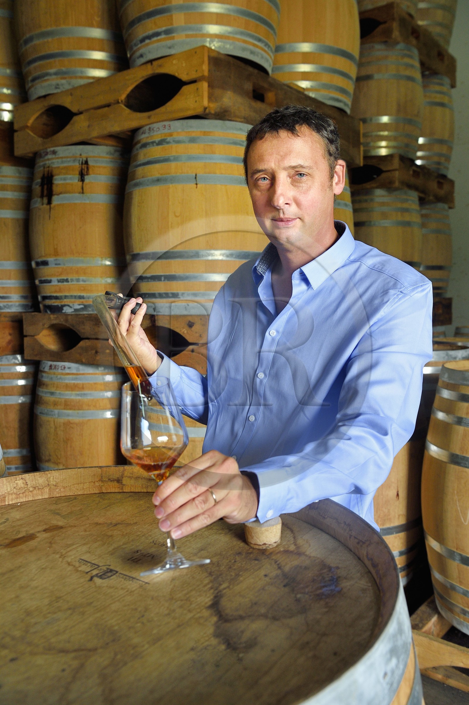 France, Ile de la Reunion, Saint Pierre, domaine de la distillerie Isautier, vieillissement des rhums vieux dans les chais entre 6 et 14 mois en futs neufs puis plusieurs années ensuite par lot en futs roux, Cyril Isautier directeur de la branche rhums et punchs du groupe Isautier fait un prélèvement à la pipette pour une dégustation