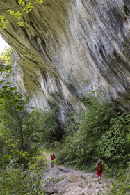France, Vaucluse (84), Parc naturel régional du Mont Ventoux, Monieux, Gorges de La Nesque, randonneurs passant sous une barre rocheuse au fond du canyon