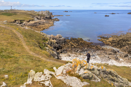 France, Finistère (29), Mer d'Iroise, Ile d'Ouessant, randonneur sur le chemin cotier de la cote dechiquetée et les rochers de la cote Nord, le phare du Créac'h en arrière plan (vue aérienne)