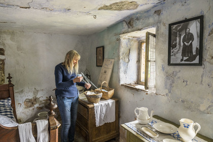 France, Bas Rhin, Parc regional des Vosges du nord (Northern Vosges Regional Natural Park), Eschbourg, Maisons des Rochers (Rocks houses) of Graufthal, semi-troglodytic houses of the 18th century and inhabited until 1958, the former village teacher Annette Oster demonstrates how to use an affiquet to knit