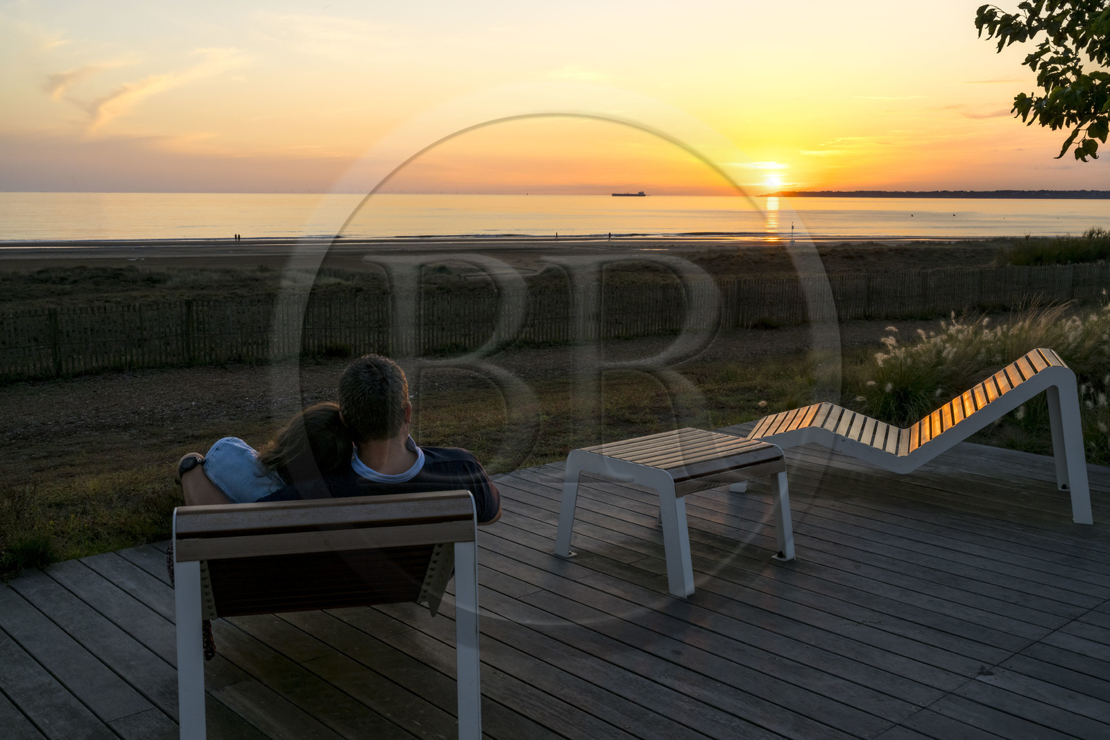 France, Loire-Atlantique (44), Saint-Brévin-Les-Pins, couple sur un banc de la promenade de bord de mer, navire quittant l'estuaire de la Loire pour l'océan en arrière plan
