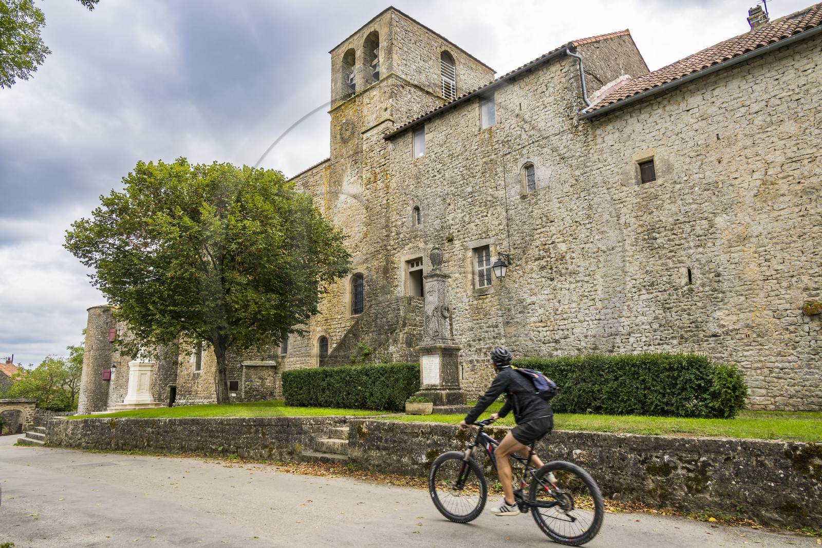 France, Aveyron (12), parc naturel régional des Grands Causses, cyclistes effectuant l'itinéraire cyclo touristique Brebis'Cyclette en Pays de Roquefort, le fort cistercien de Saint-Jean-d’Alcas, église  Saint-Jean de l'ancienne abbaye de Nonenque