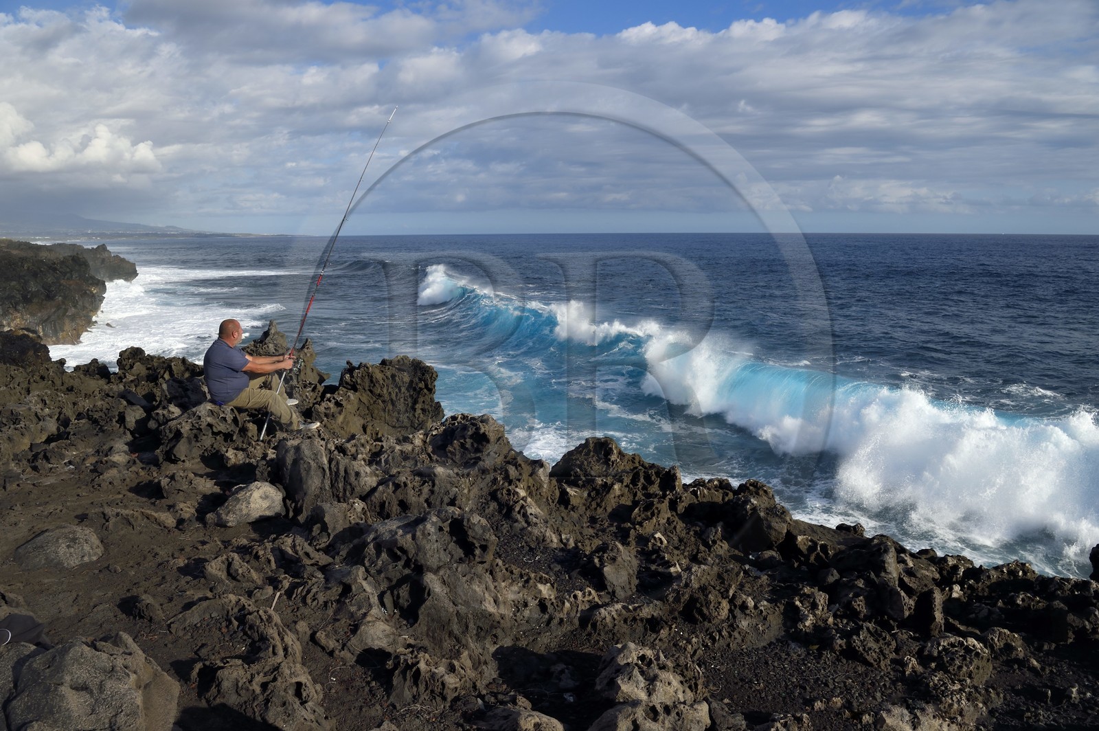 France, Ile de la Reunion, L'Etang Salé les Bains, la côte entre Le Gouffre et l'Etang du Gol, roches noires basaltiques d'origine volcanique tourmentées par l'océan, pêcheur à la ligne