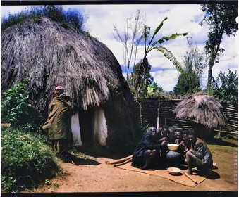 Burundi, province de Bujumbura, région d'Ijenda, habitation principale d'un rugo de type intermédiaire, le rugo archaïque (pré colonial) à quasiment disparu, cette hutte hémisphérique s'en différencie uniquement par le fait d'avoir des murs en dur, l'organisation intérieure n'a pas changé et elle conserve son toit en chaume qui la recouvre entièrement, les deux hommes à gauche et à droite en premier plan sont probablement Hutu alors que les autres hommes et la femme sont Tutsi, les deux ethnies cohabitent sans problèmes en temps de paix et ont des relations de bon voisinage, les hommes sont en train de boire de la bière de sorgho (bière traditionnelle) (reproduction plan-film inversible 4x5)