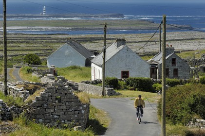 Republic of Ireland, County Galway, Aran Islands, Inishmore, cyclist on the western headland of the island, facing Brannock Islands