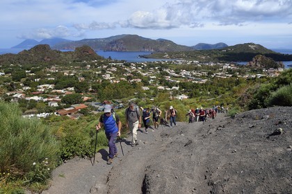 Italy, Sicily, Aeolian Islands, listed as World Heritage by UNESCO, Vulcano Island, hikers climbing the crater of volcano della Fossa, the island of Lipari then Salina island in the background