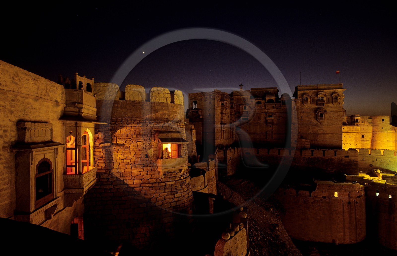 India, Rajasthan State, Jaisalmer fort, the Raj Mahal Palace and the lighted window of the small French owned hotel Kila Bhawan in the old walls off the city