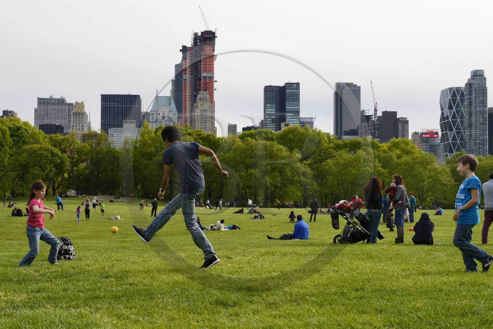 Etats-Unis, New York, Manhattan, Central Park, enfants jouant au football sur le Sheep Meadow, immeubles de Central Park Sud en arrière plan