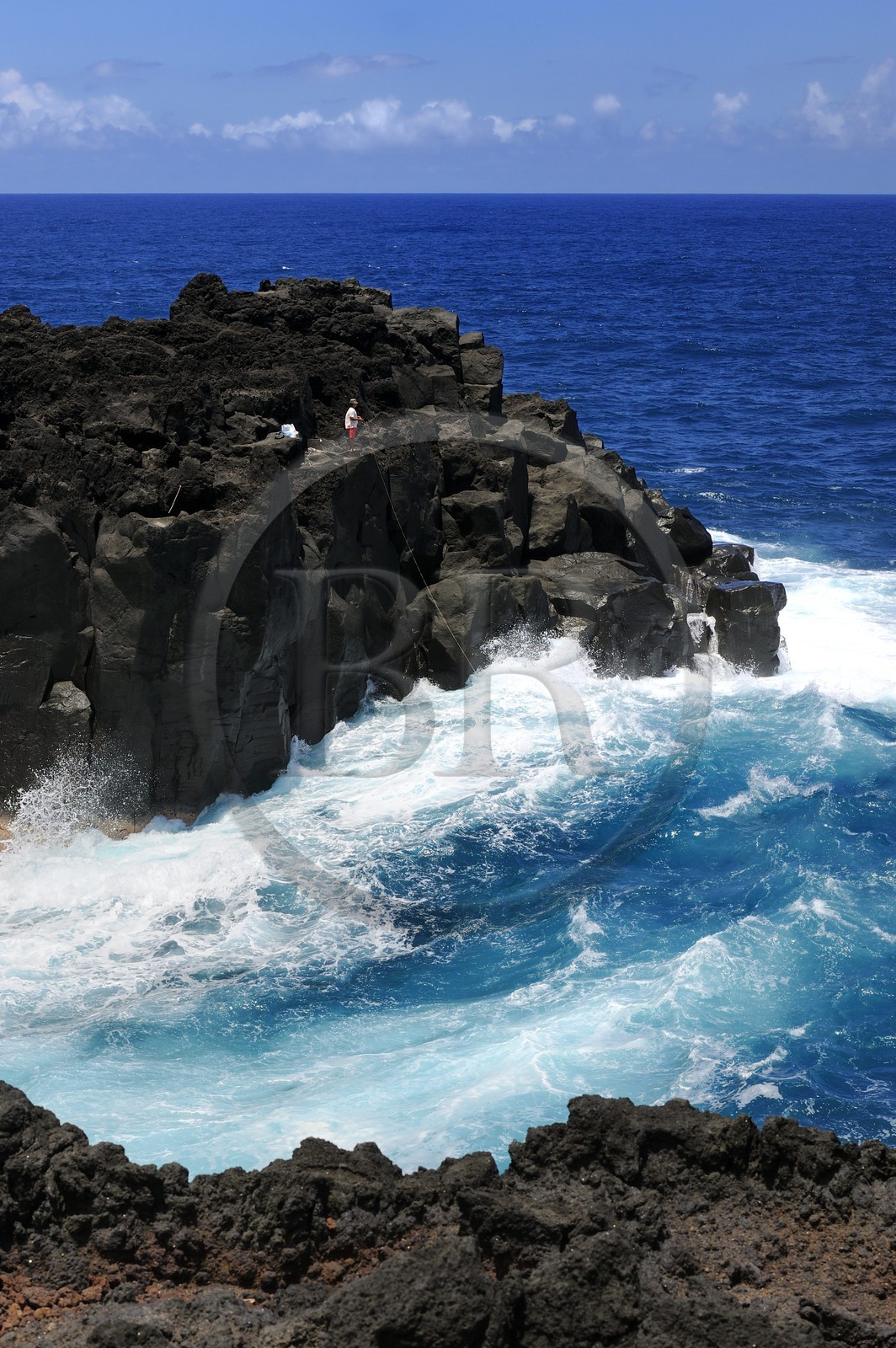 France, Ile de la Reunion, côte sud, Saint-Philippe, le Cap Méchant est situé le long d'une côte déchiquetée de roche volcanique frappée par la houle et typique de la région appelée Sud sauvage, pêcheur sur un rocher