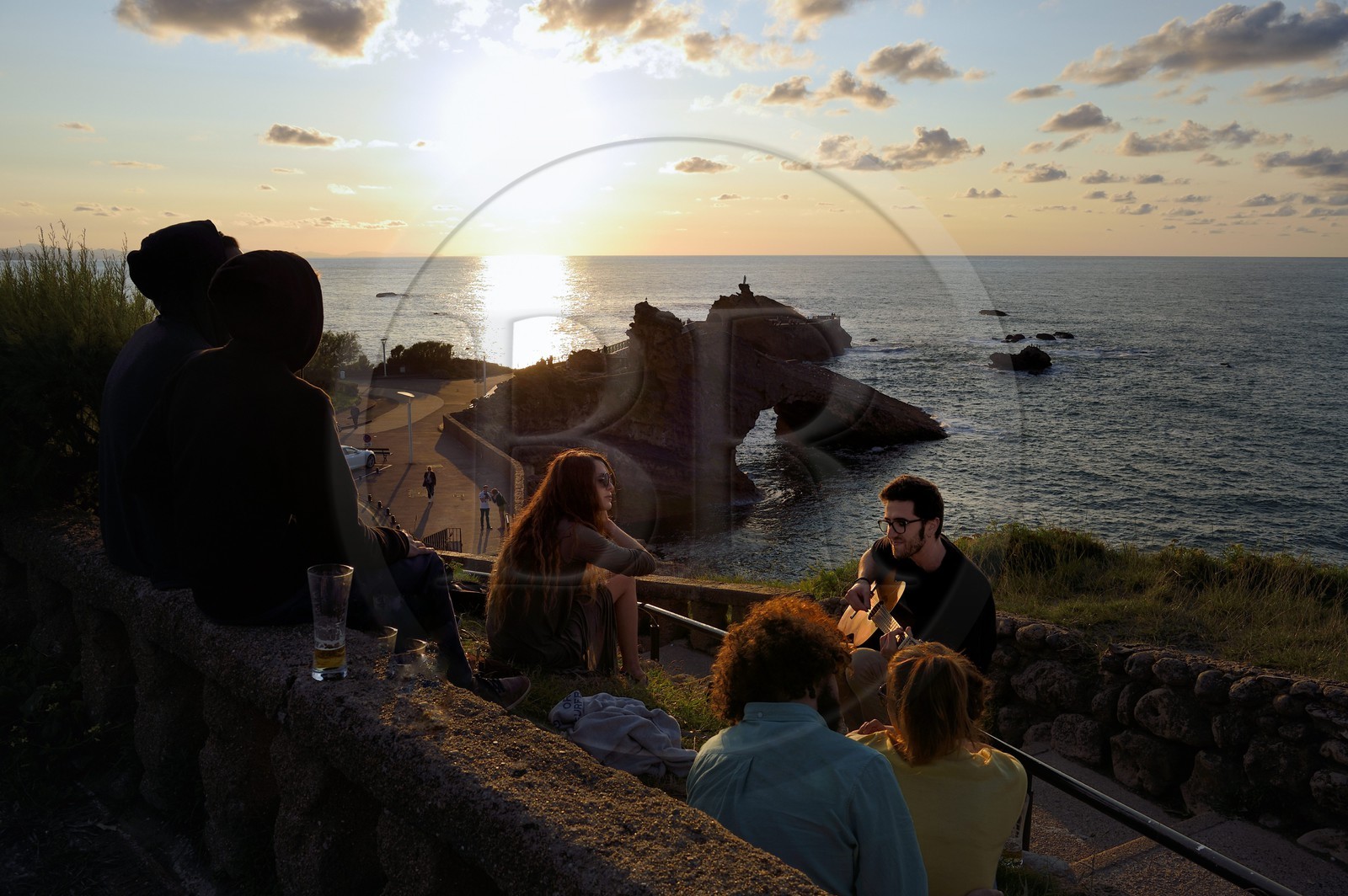 France, Pyrénées-Atlantiques (64), Pays-Basque, Biarritz, jeunes gens jouant de la guitare au coucher du soleil, le Rocher de la Vierge en arrière plan