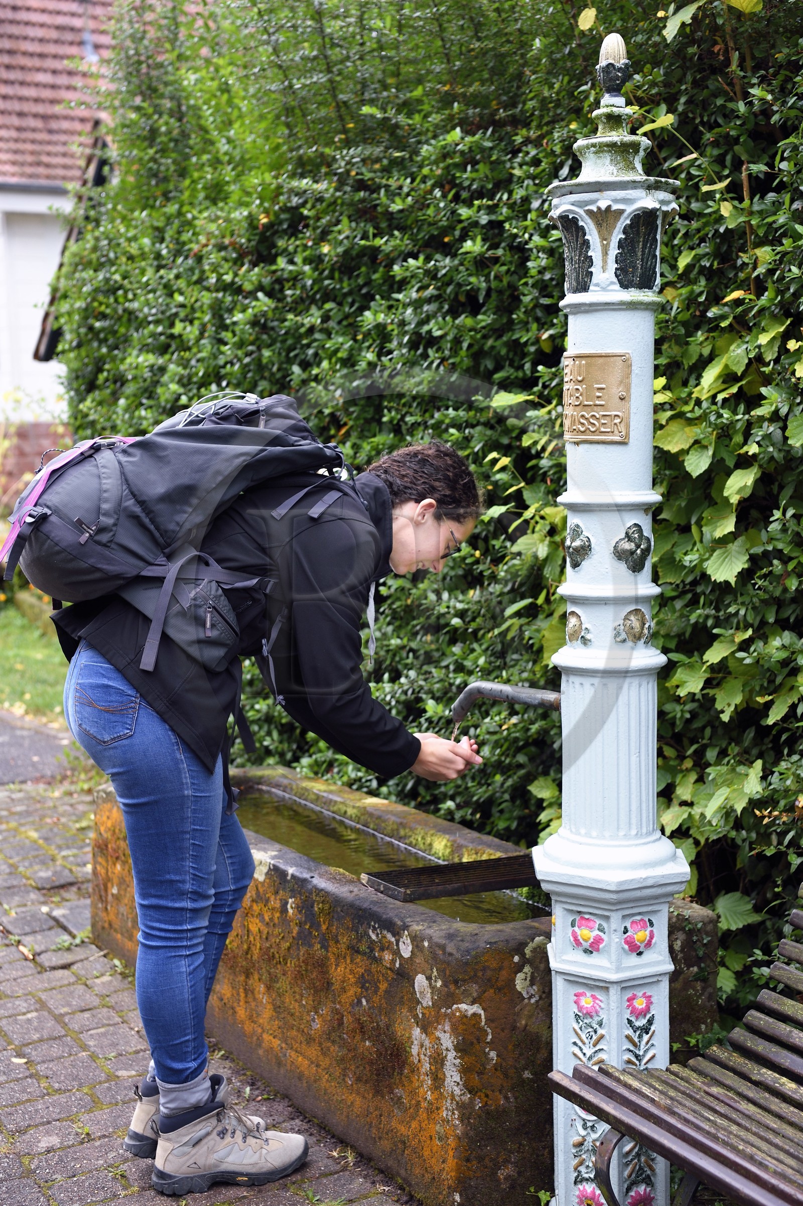 France, Bas-Rhin (67), Parc naturel régional des Vosges du Nord, Niedersteinbach, randonneuse buvant à une des nombreuses fontaines du village