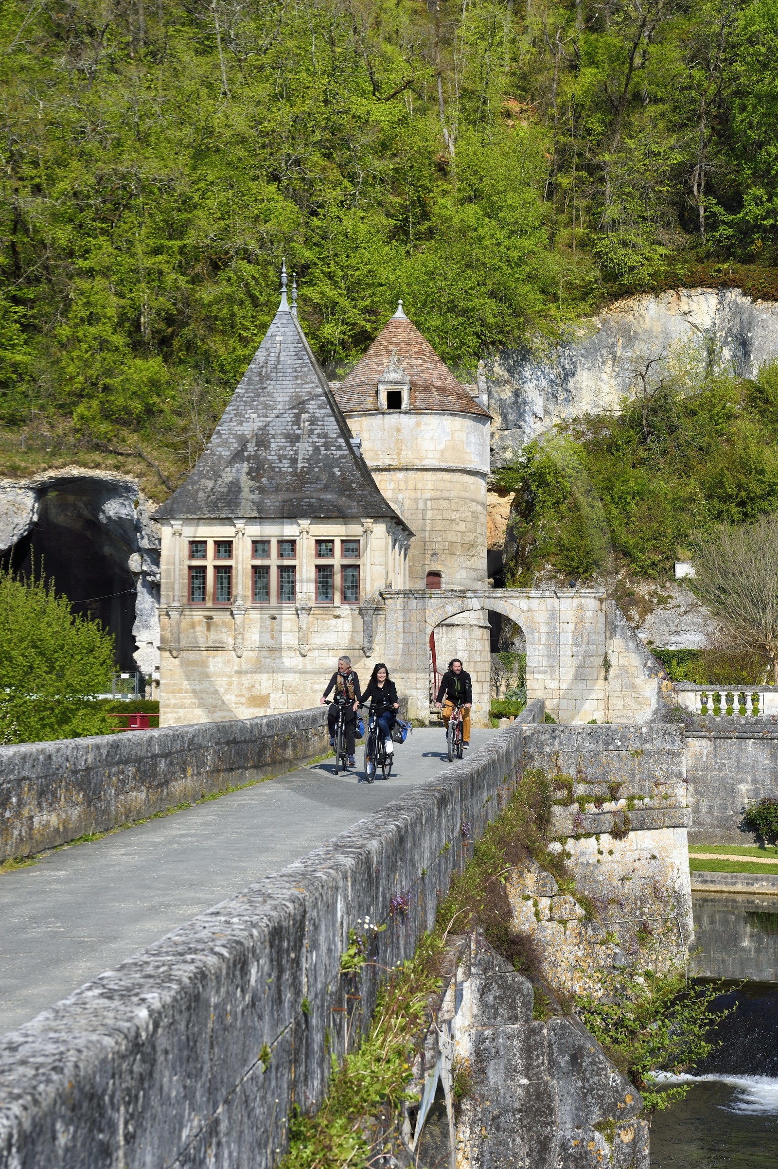 France, Dordogne (24), Brantôme, Pont Coudé sur la Dronne de l'abbaye bénédictine Saint-Pierre de Brantôme, le pavillon Renaissance et la tour qui formaient la porte fortifiée en arrière plan, cyclistes sur la véloroute la Flow Vélo