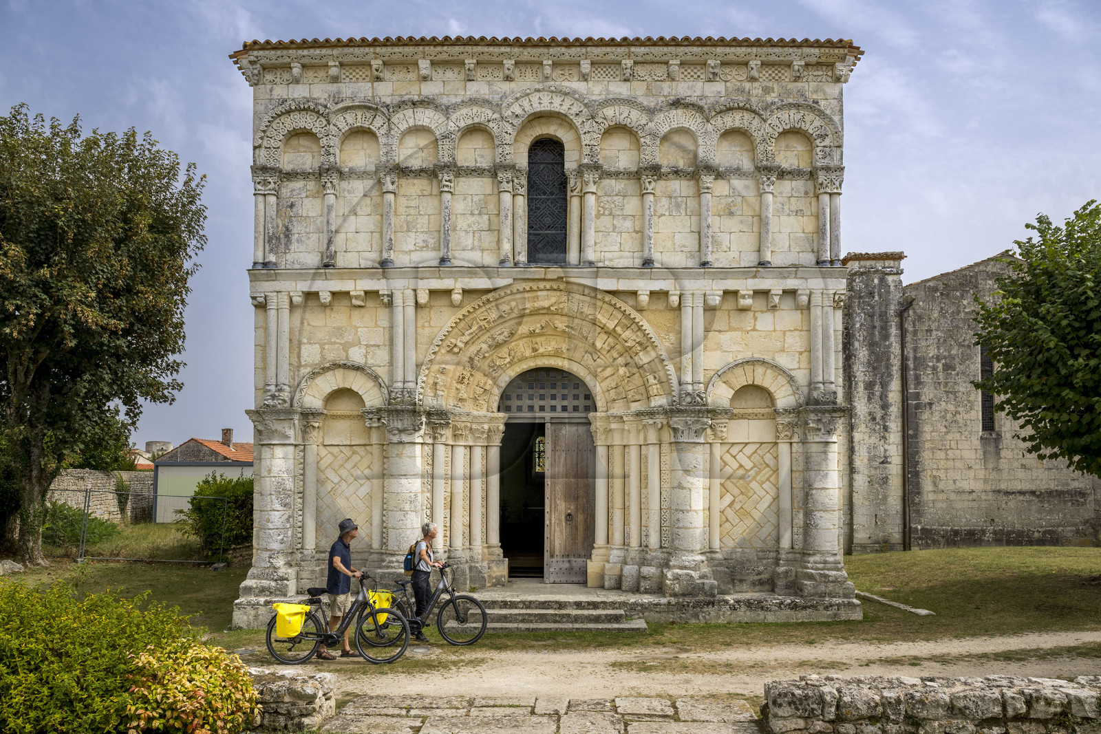 France, Charente Maritime, Echillais, cyclists traveling along the cycle route in front of the 12th century Romanesque church of Notre-Dame, classified as a historic monument