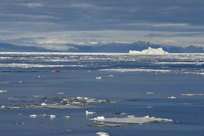 Groenland, cote Nord-Ouest, Smith sound au nord de la baie de Baffin, morceaux de glace de la banquise arctique et un PolarCirkel boat (zodiac) d'exploration du bateau de croisière MS Fram de la compagnie Hurtigruten, iceberg géant en arrière plan vers la côte canadienne de l'ile d'Ellesmere