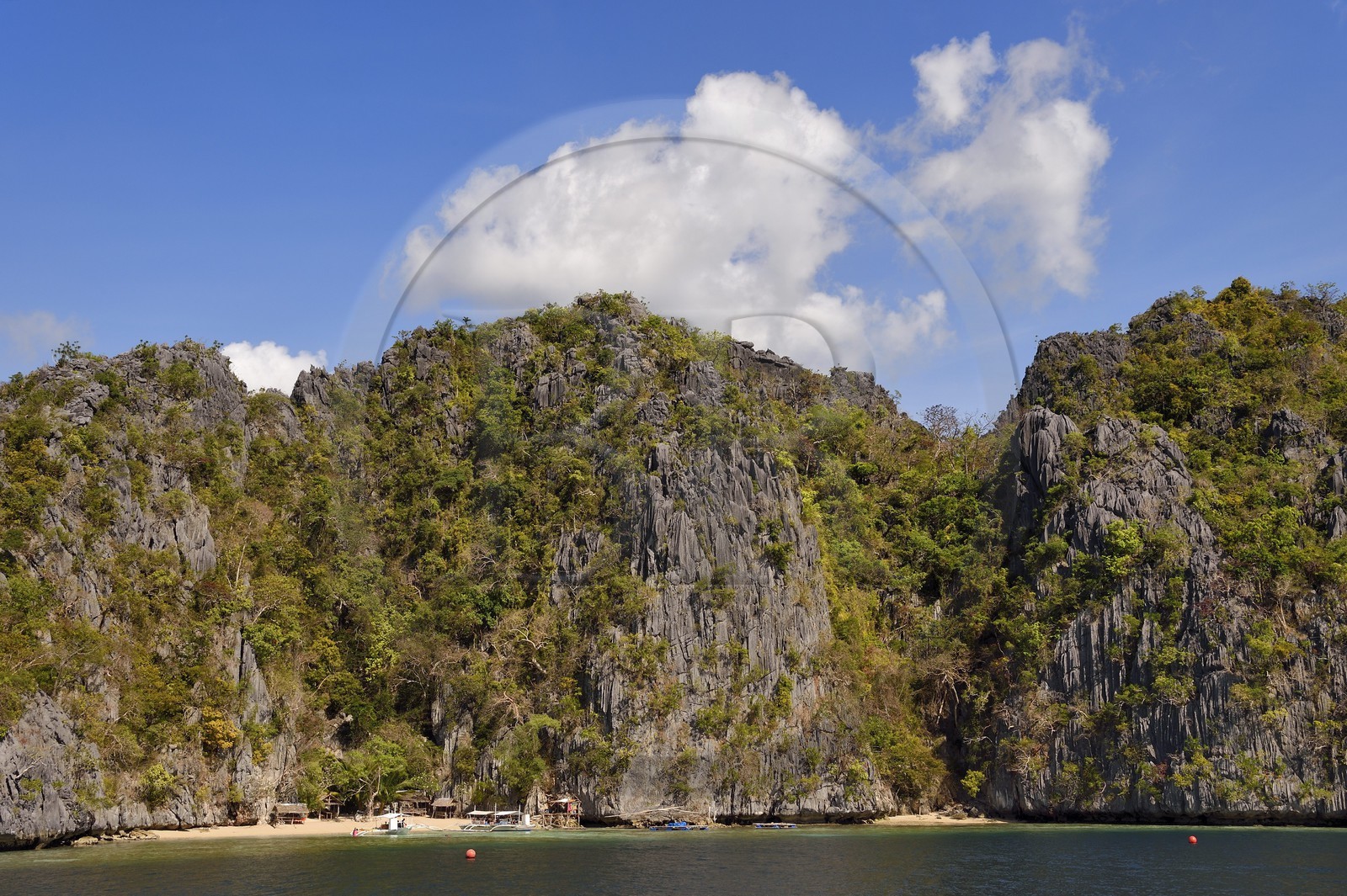 Philippines, Calamian Islands in northern Palawan, Coron Island Natural Biotic Area, Outrigger canoe under giant walls of limestone cliffs
