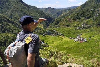 Philippines, province d'Ifugao, randonneur surplombant les rizières en terrasses de Banaue autour du village de Batad, classées Patrimoine Mondial de l'UNESCO, logo Nomade Aventures