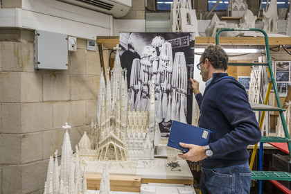 Spain, Catalonia, Barcelona, Eixample district, Sagrada Familia basilica by Catalan modernist architect Antoni Gaudi, listed as a UNESCO World Heritage Site, the model workshop, Architect and coordinator of the team of artists and model makers Jeronimo Buxareu Padros presents the next works to be undertaken, the future Glory facade in front of him and the photo of the original Gaudi model in the background