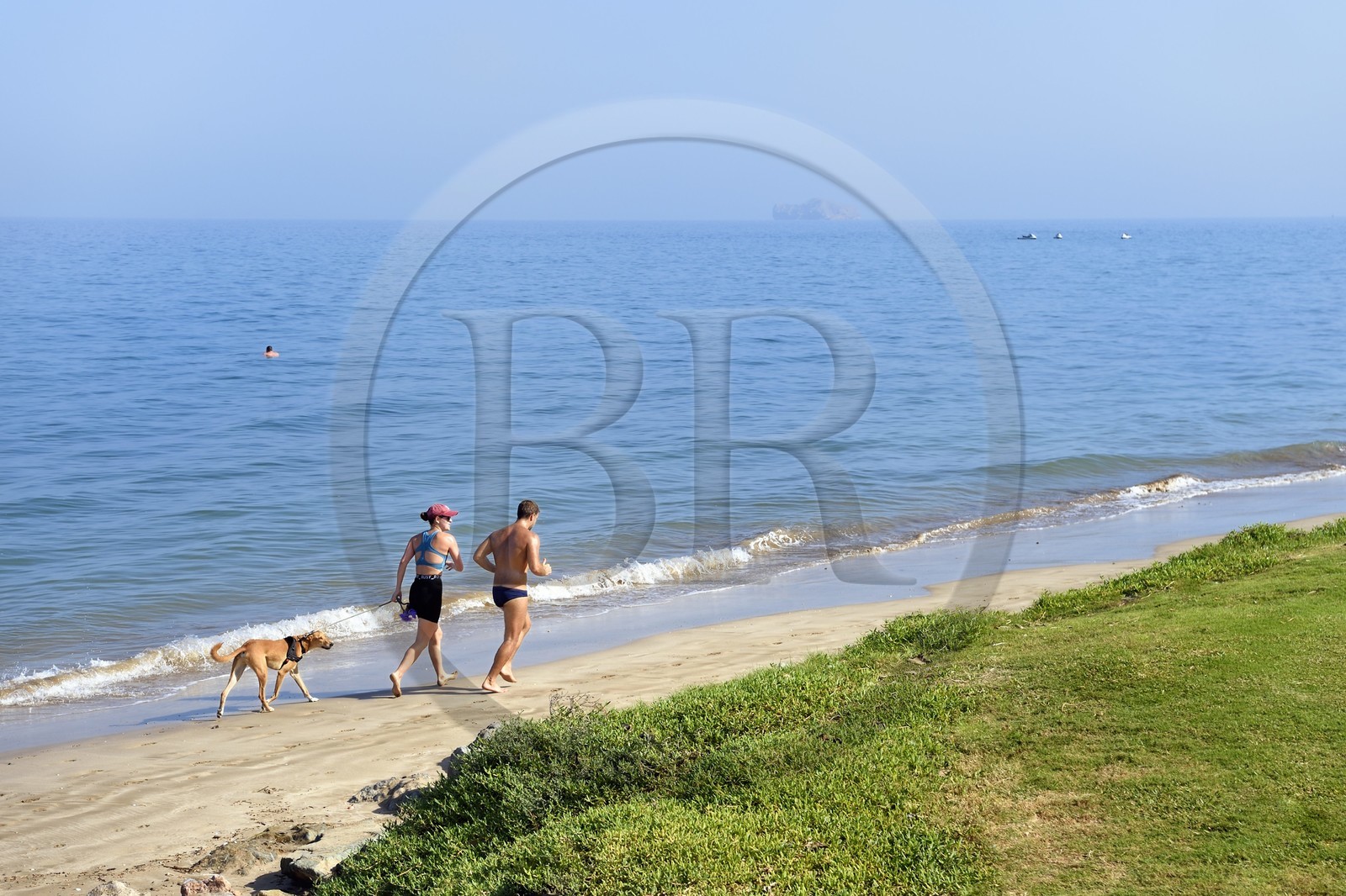 Sultanate of Oman, Muscat, couple avec un chien courant sur la plage de la Madinat Al Sultan Qaboos