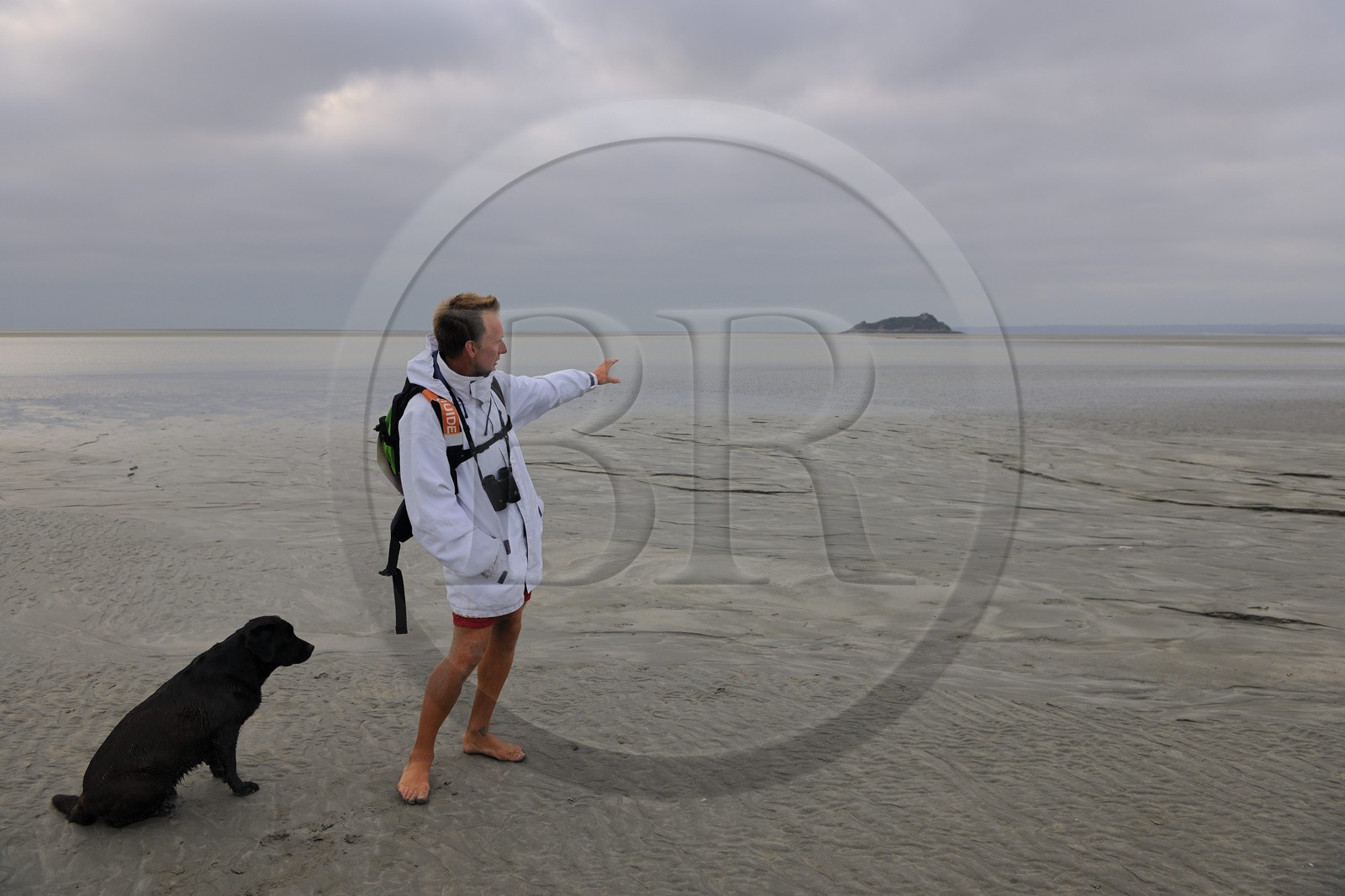France, Manche (50), découverte de la Baie du Mont-Saint-Michel à pied avec le guide Romain Pilon qui pointe l'ile de Tombelaine
