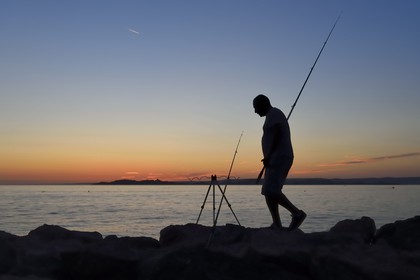 France, Bouches-du-Rhône (13), Marseille, La Madrague, pêcheur au coucher de soleil face au Frioul