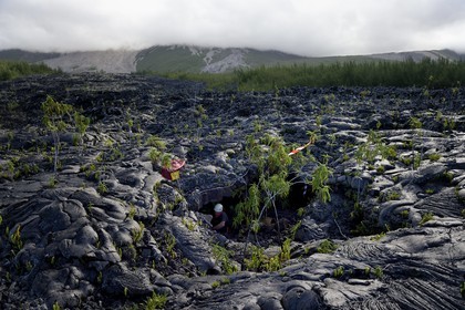 France, Reunion island (French overseas department), Piton de la Fournaise, listed as World Heritage by UNESCO volcano, the Grand Brule, recent lava flow and the volcano in the background, firefighter at the entrance of a lava tunnel during a rescue exercise