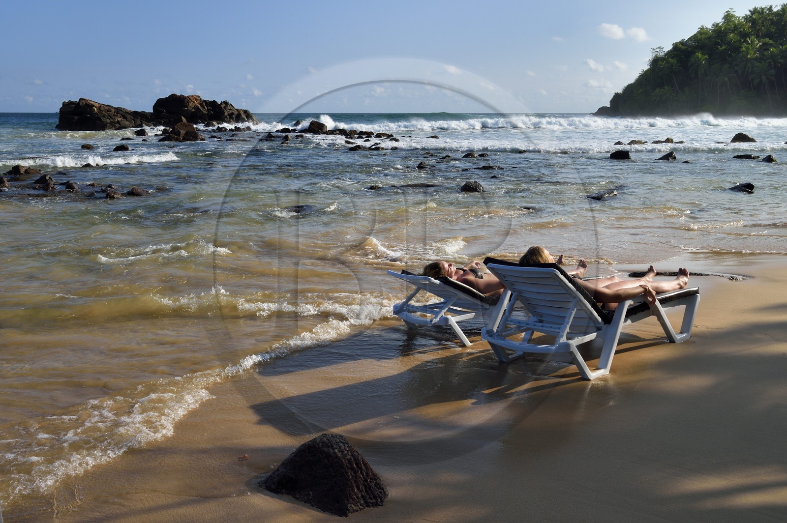Sri Lanka, Province du Sud, Matara (district), Weligama, plage de Mirissa, femmes bronzant sur une chaise longue les pieds dans l'eau