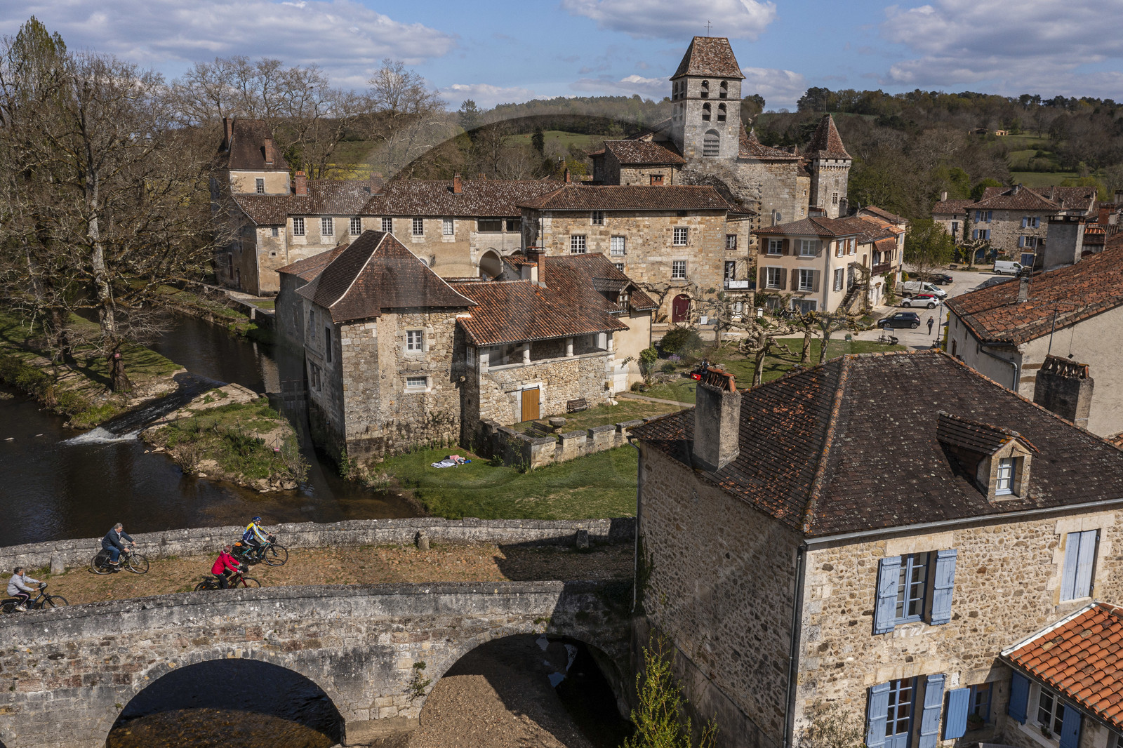 France, Dordogne, Périgord Vert, Saint Jean de Cole, labelled Les Plus Beaux Villages de France (The Most Beautiful Villages of France), cyclists on the Flow Vélo cycle route crossing the medieval bridge of the 12th century, the St. John the Baptist (Saint-Jean-Baptiste) church bell tower (aerial view)