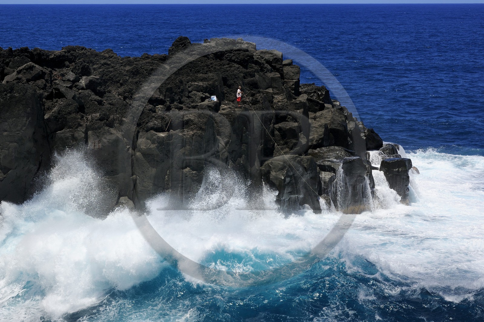 France, Ile de la Reunion, côte sud, Saint-Philippe, le Cap Méchant est situé le long d'une côte déchiquetée de roche volcanique frappée par la houle et typique de la région appelée Sud sauvage, pêcheur sur un rocher