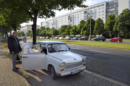 Germany, Berlin, Karl-Marx Allee is the largest artery of the country leading from Alexanderplatz to Frankfurter Tor and the communist regime annually paraded his army there, family getting into their car Trabant